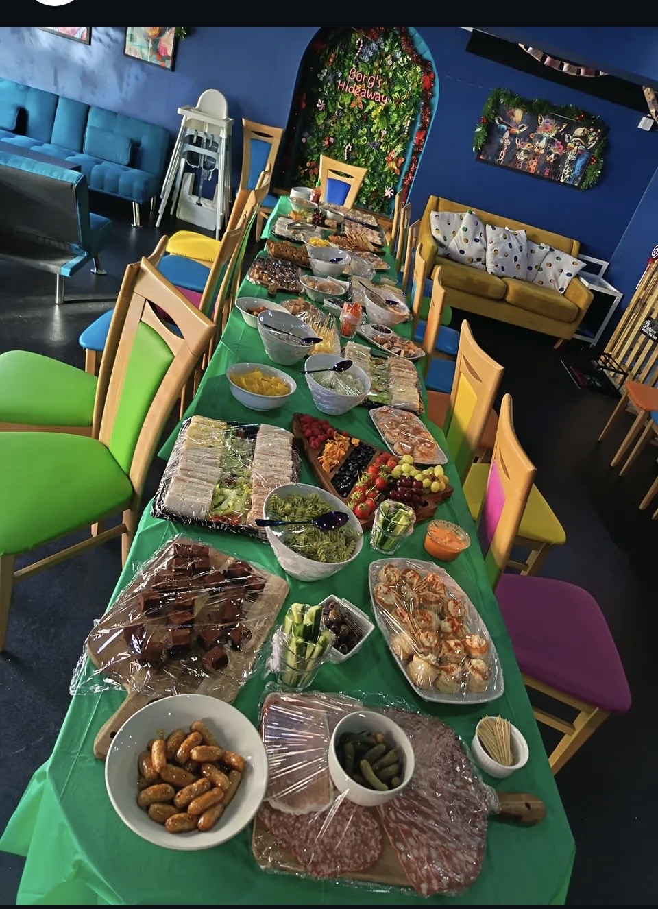 Long buffet table laid out with sandwiches, brownies, fruit and meats for an event